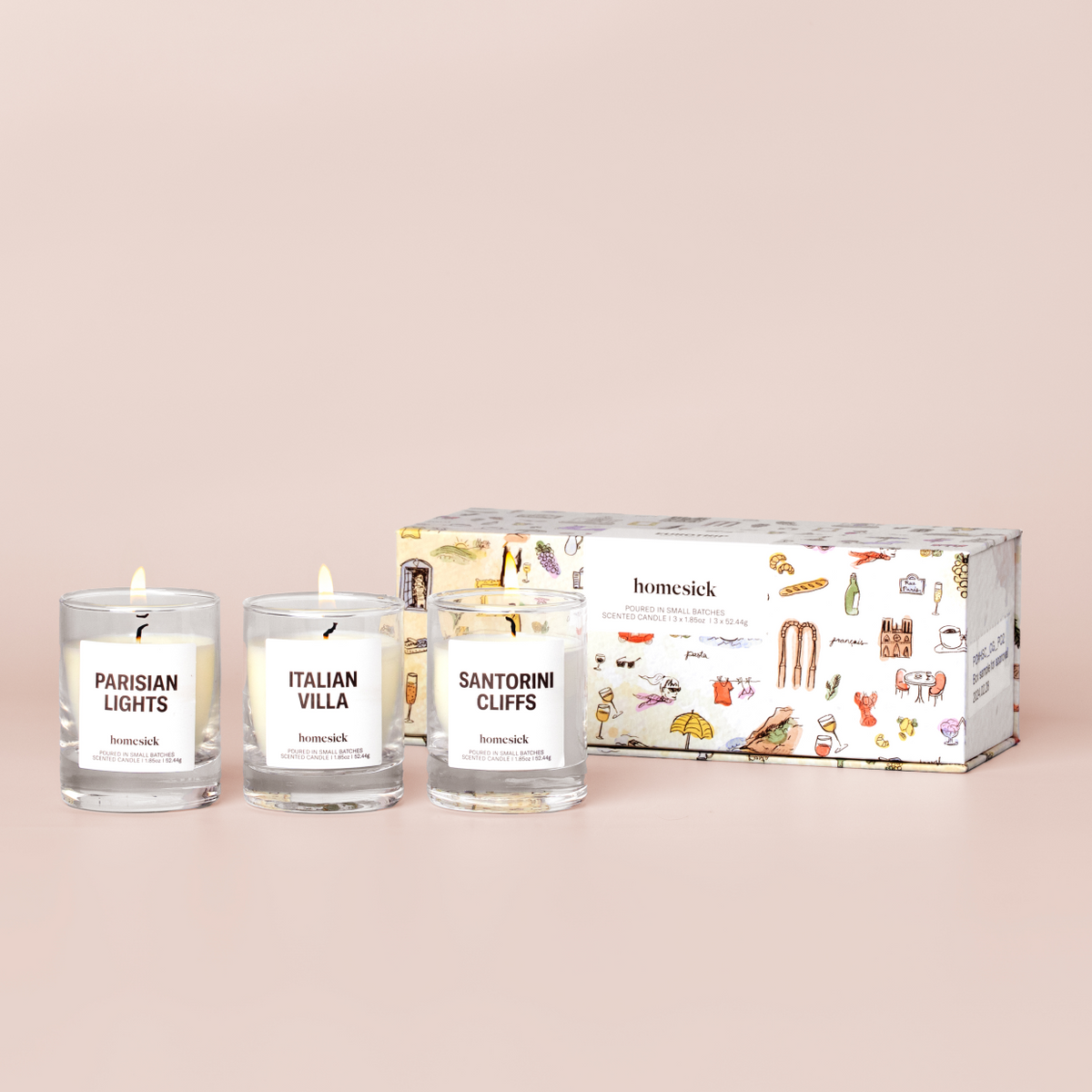 three mini candles labelled "Sanitorini Cliffs", "Italian Villa", and "Parisian Lights" and a box on a cream background