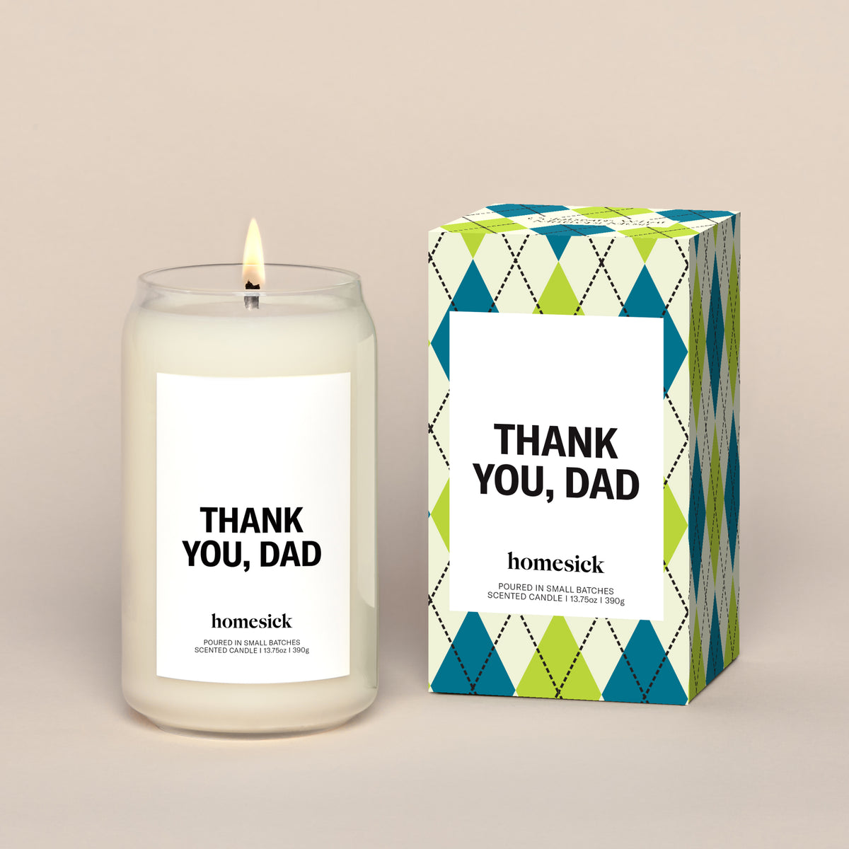 A lit Thank You, Dad Homesick candle displayed next to its boxed packaging on a dark cream background.