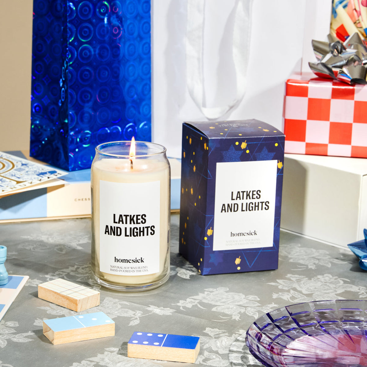 The Latkes and Nights candle next to its packaging shot in the midst of a table with celebratory Hanukkah items.