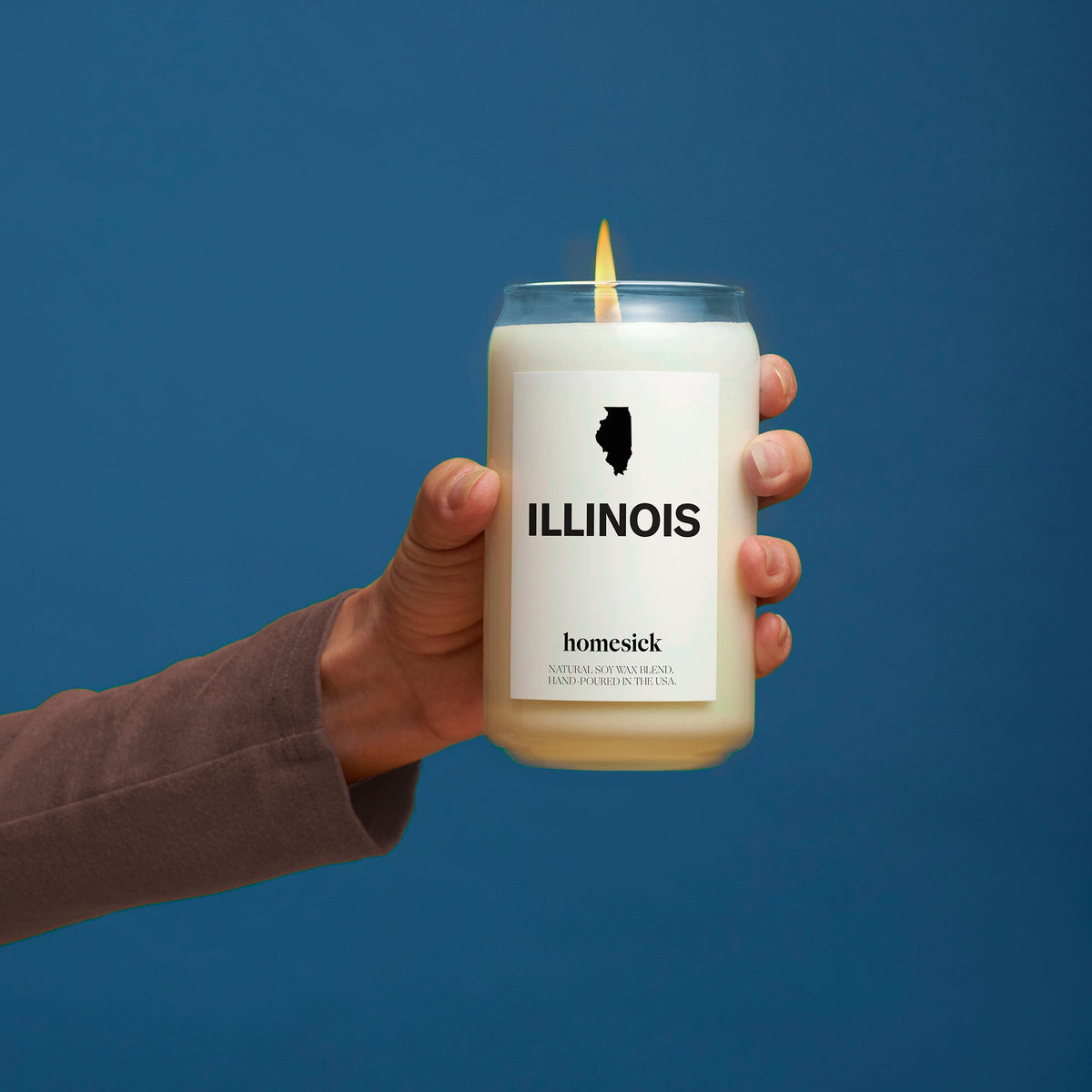 A hand holding an Illinois Candle in front of a blue background.