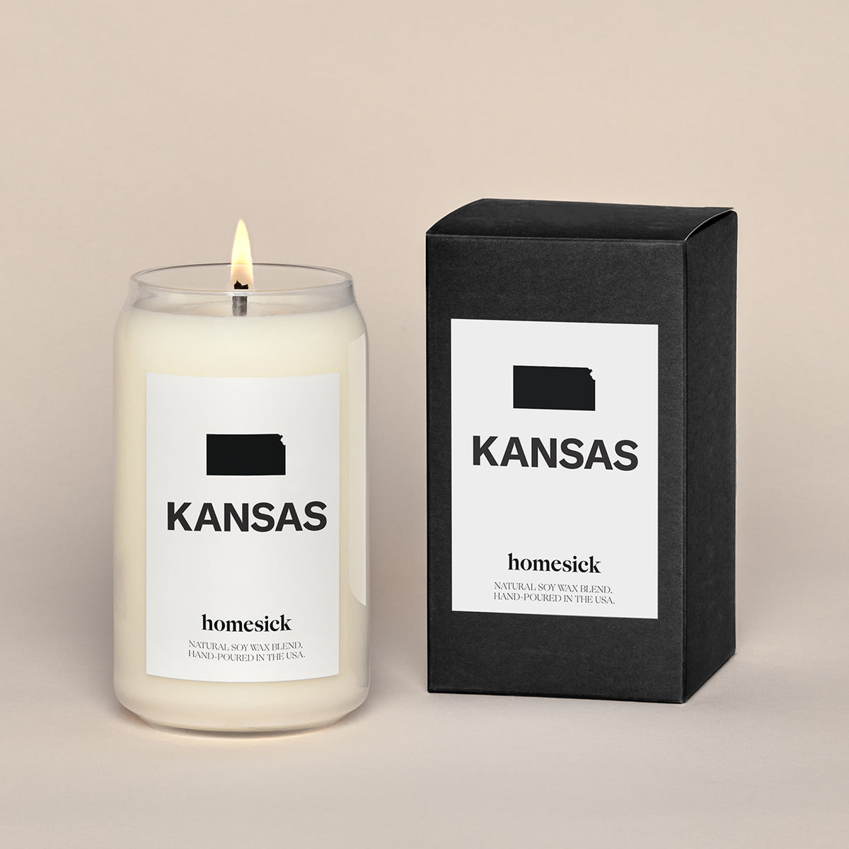 A lit Kansas Homesick candle displayed next to its boxed packaging on a dark cream background.